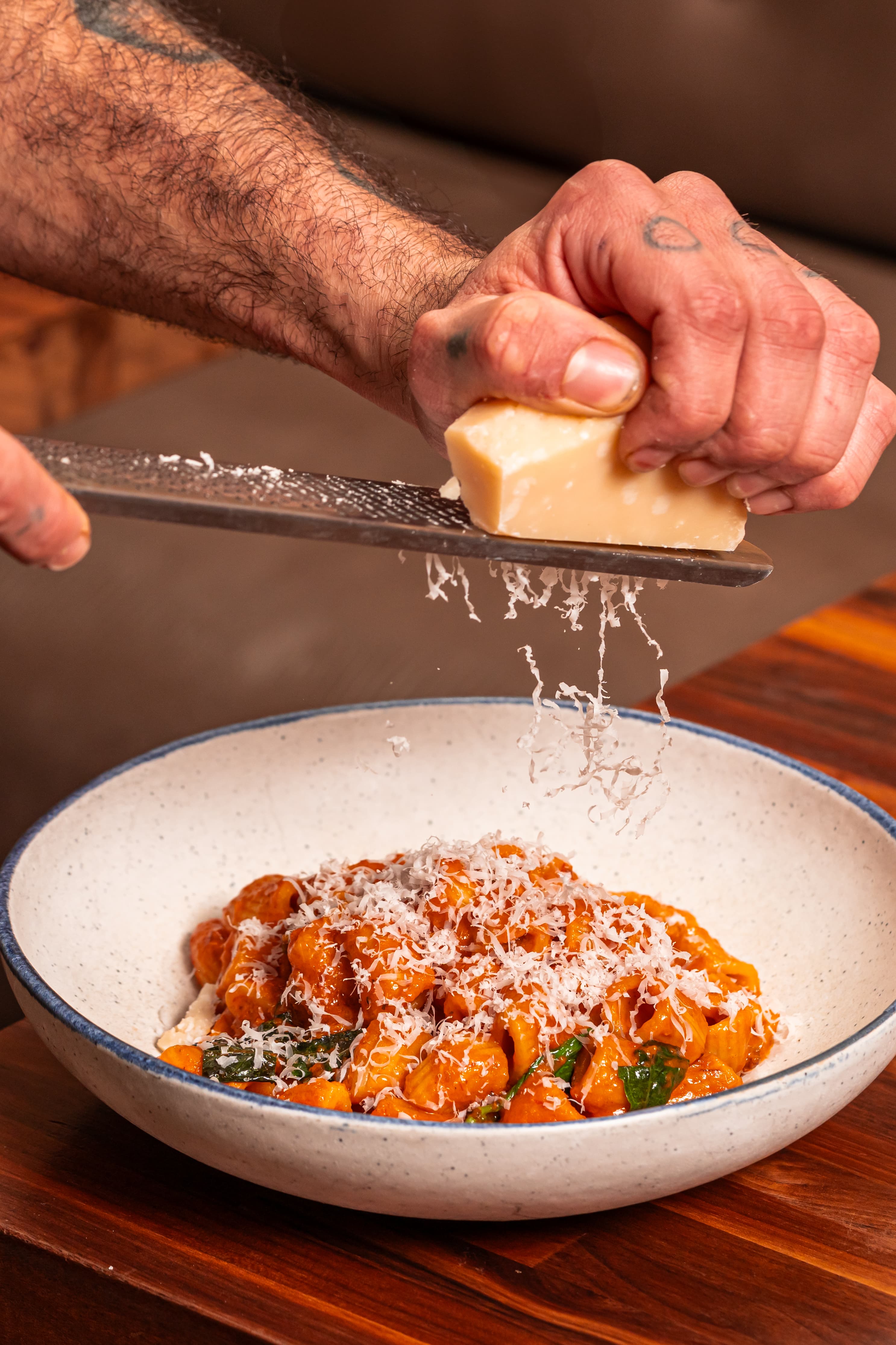 Chef grating parmesan over rigatoni